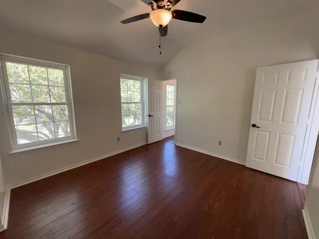 a view of an empty room with wooden floor and a window