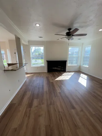 a view of an empty room with wooden floor fireplace and a window