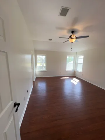 an empty room with wooden floor and windows
