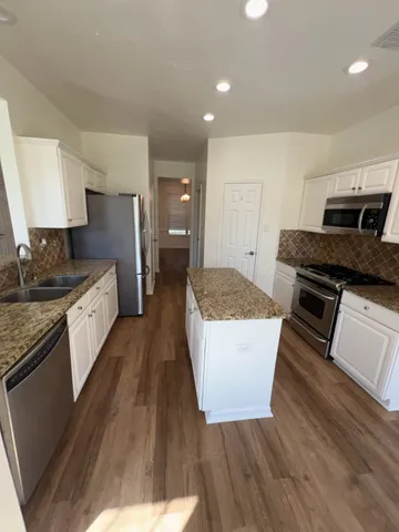 a kitchen with granite countertop a stove a sink and a refrigerator