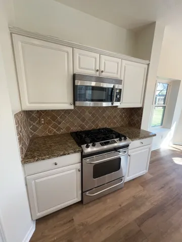 a kitchen with granite countertop white cabinets and stainless steel appliances