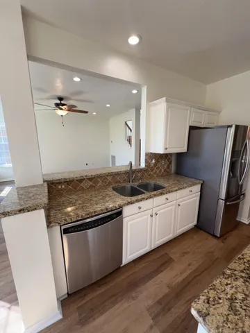 a large kitchen with stainless steel appliances granite countertop a stove a sink dishwasher and a refrigerator with wooden floor