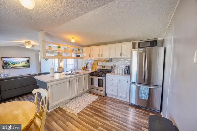 a kitchen with granite countertop a refrigerator stove and wooden floor