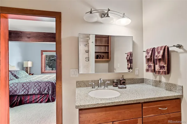 a en suite bathroom with a granite countertop sink and a mirror