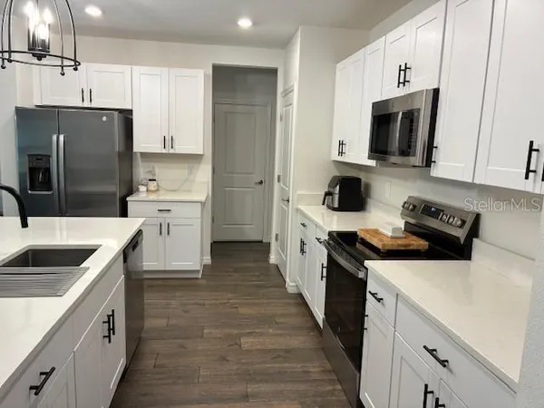 a kitchen with stainless steel appliances kitchen island granite countertop a stove a sink a refrigerator and white cabinets