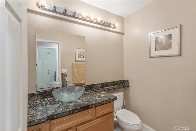 a bathroom with a granite countertop sink a toilet and mirror