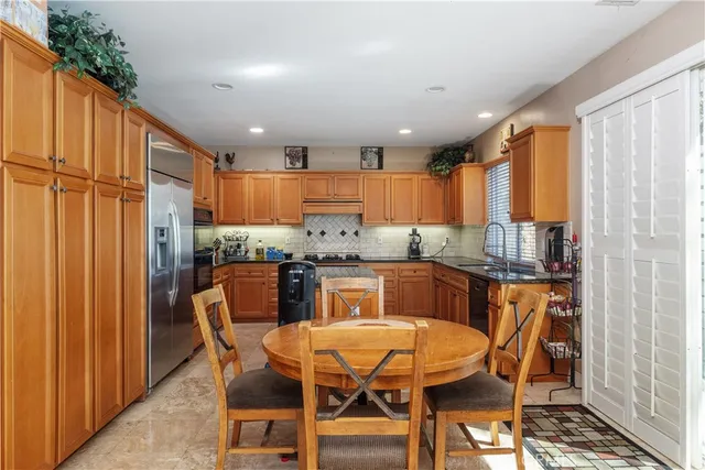 a kitchen with stainless steel appliances kitchen island granite countertop a table chairs and a refrigerator