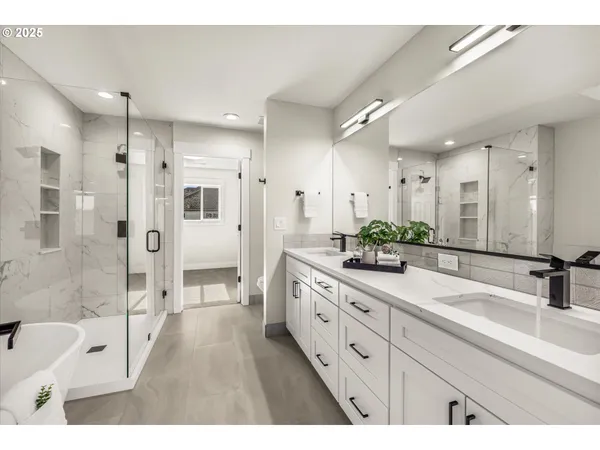 a spacious bathroom with a double vanity sink a large mirror a shower and bathtub