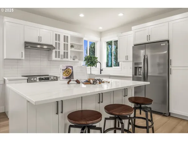 a kitchen with stainless steel appliances a table chairs and a refrigerator
