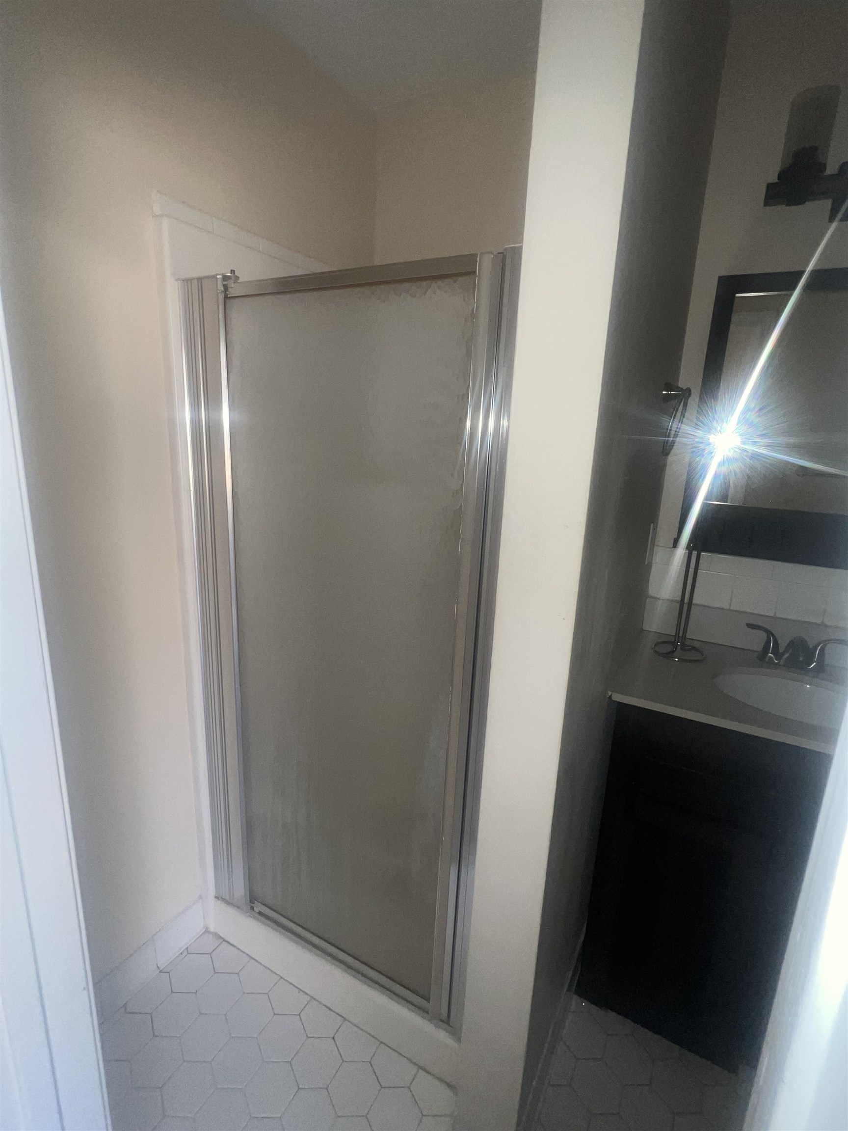 4295 Hudgins Road Memphis, TN 38116 - Photo 5 of 16 Frosted glass shower enclosure with a chrome frame and white hexagonal tile flooring