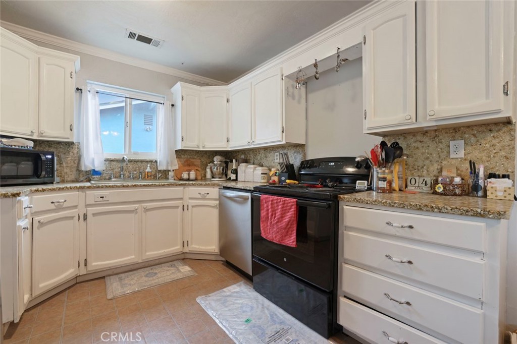 424 Morada Lane Stockton, CA 95210 - Photo 24 of 51 a kitchen with granite countertop white cabinets and black appliances