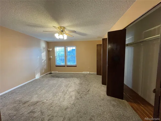 an empty room with windows and a chandelier fan