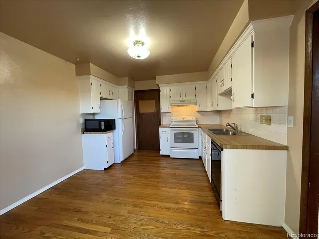 a kitchen with cabinets and wooden floor