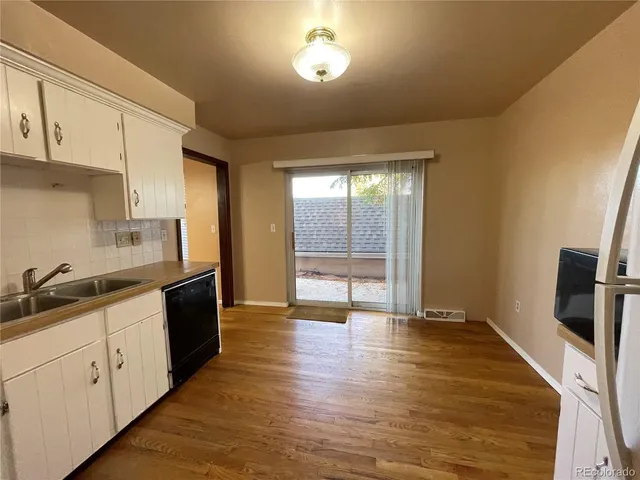 a kitchen with stainless steel appliances granite countertop a sink and cabinets with wooden floor