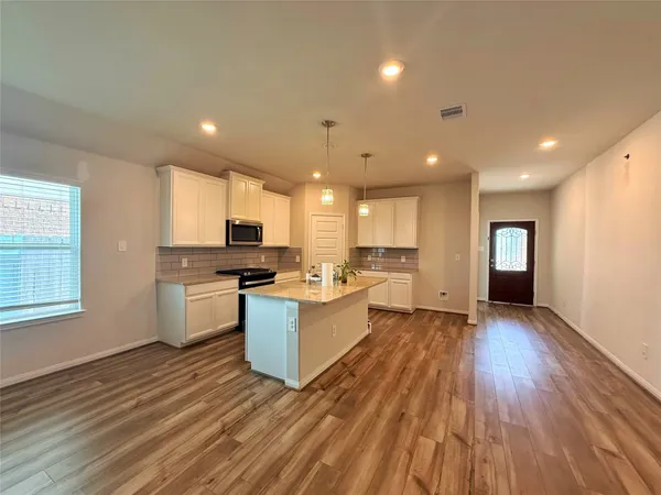 a large kitchen with a center island wooden floor stainless steel appliances and windows