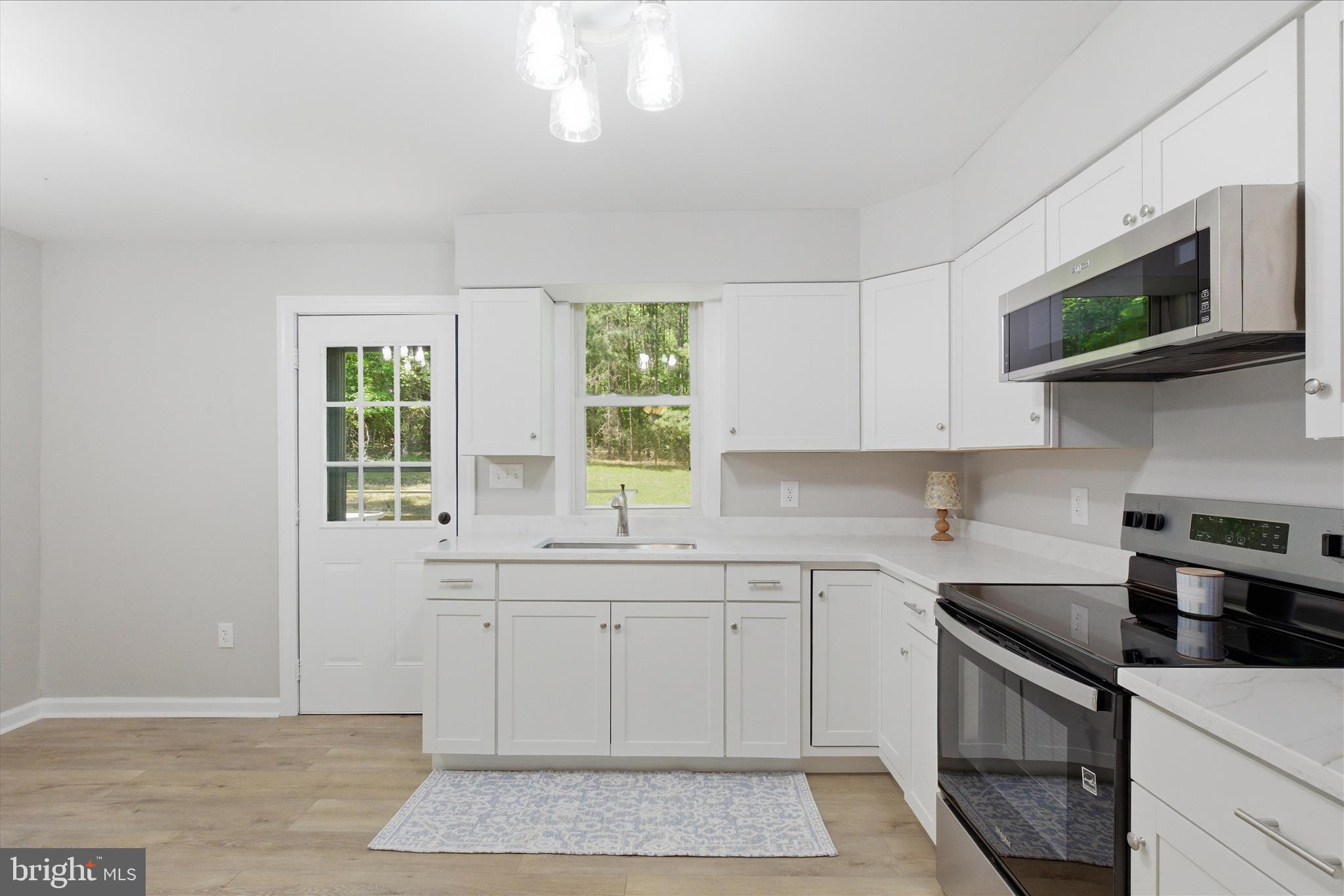 6815 Marshall Road St. Leonard, MD 20685 - Photo 13 of 43 a kitchen with stainless steel appliances white cabinets and a stove top oven