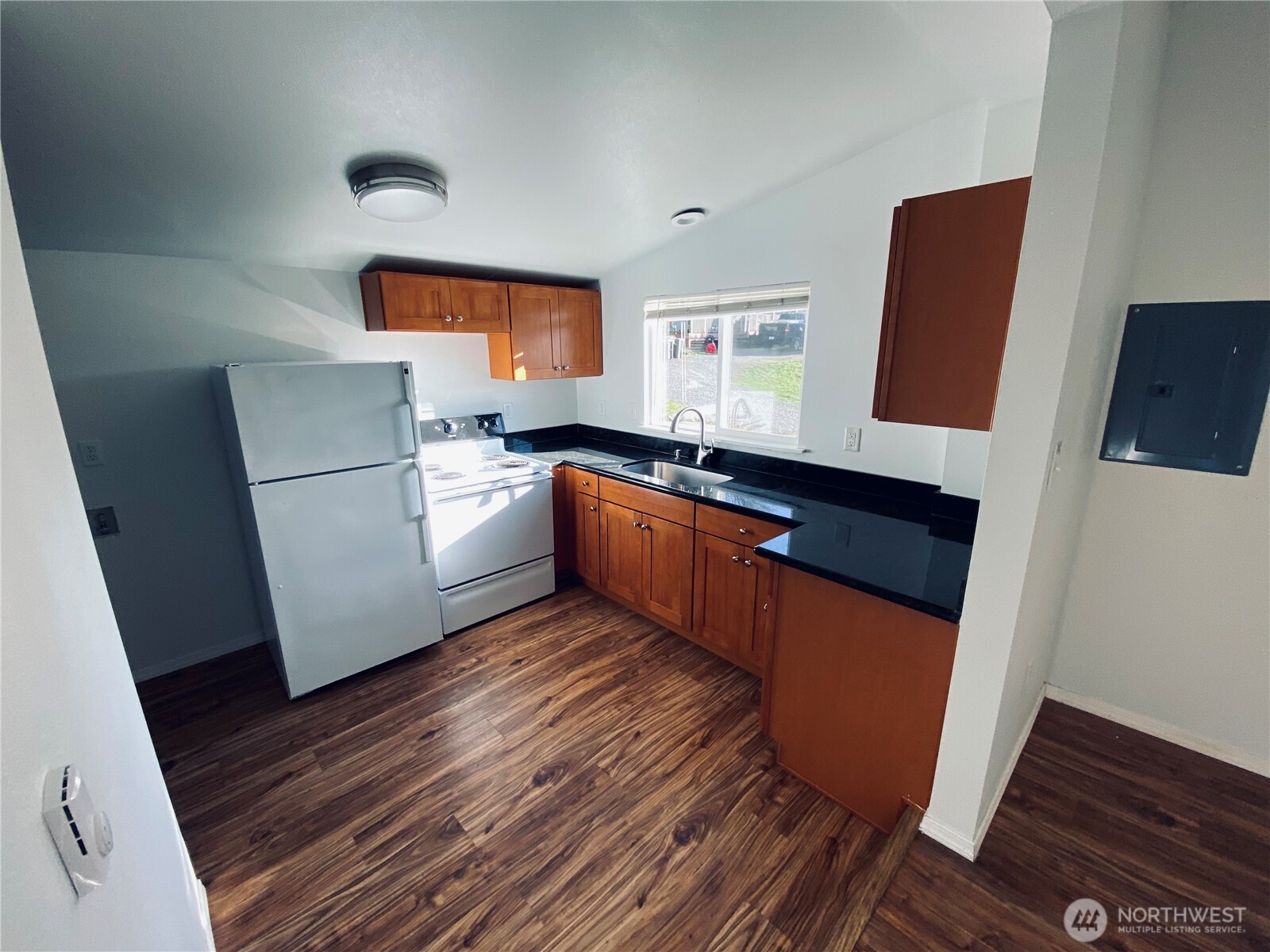 20314 Gun Club Road, Unit B Granite Falls, WA 98252 - Photo 4 of 10 a kitchen with granite countertop a refrigerator a sink dishwasher a stove and white countertops with wooden floor