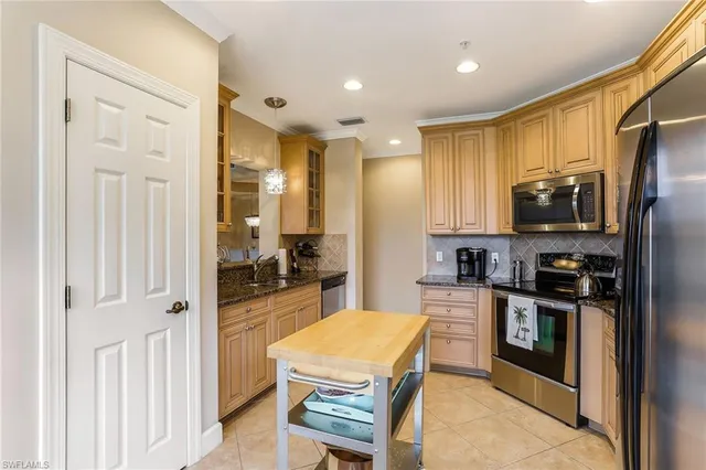 a kitchen with stainless steel appliances granite countertop a refrigerator oven stove a sink dishwasher and white cabinets with wooden floor