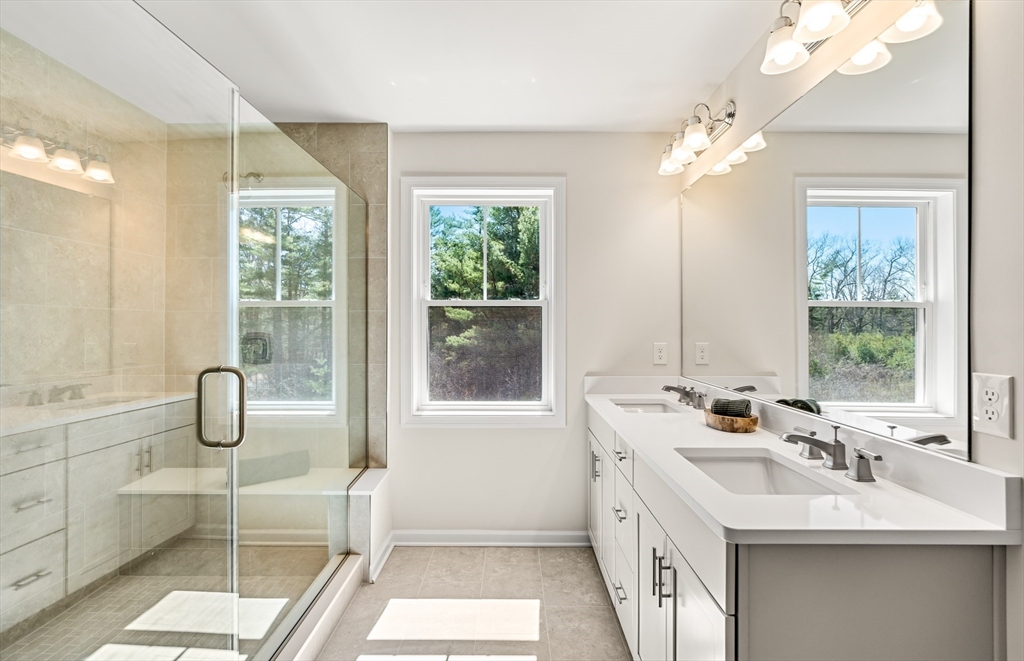 25 Sandtrap Circle, Unit 8 Walpole, MA 02081 - Photo 14 of 15 a bathroom with a double vanity sink a large mirror and a bathtub