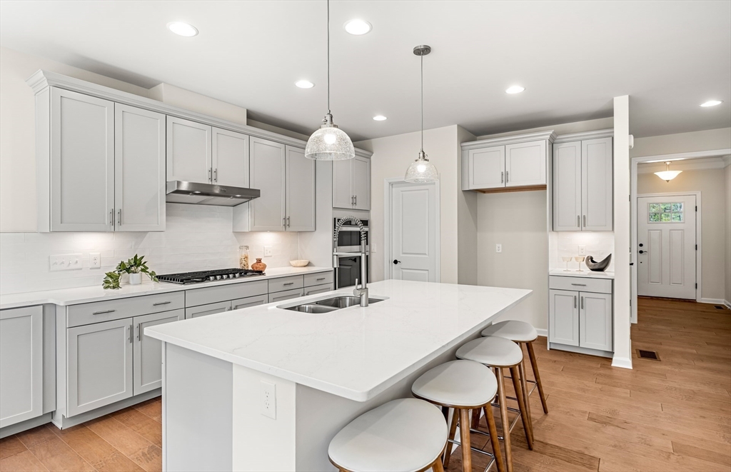 25 Sandtrap Circle, Unit 8 Walpole, MA 02081 - Photo 3 of 15 a kitchen with stainless steel appliances kitchen island a table chairs sink and cabinets