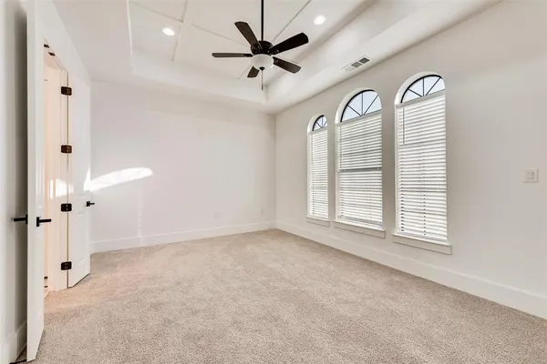 an empty room with windows and ceiling fan