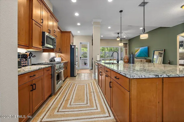 a large kitchen with granite countertop a sink and a refrigerator