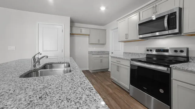 a kitchen with stainless steel appliances granite countertop a sink stove microwave and refrigerator