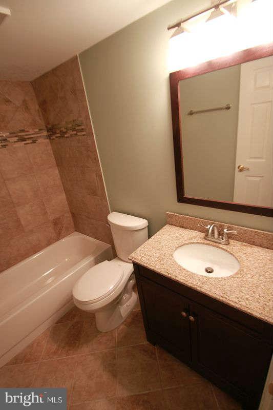 5807 Cove Landing Road, Unit 204 Burke, VA 22015 - Photo 5 of 17 a bathroom with a granite countertop toilet a sink and a mirror