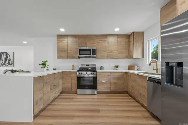 a large kitchen with stainless steel appliances granite countertop a stove a sink dishwasher and a microwave oven with white cabinets