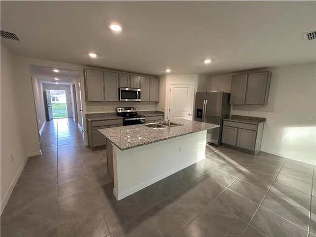 a large kitchen with stainless steel appliances granite countertop a stove a sink a refrigerator and a microwave