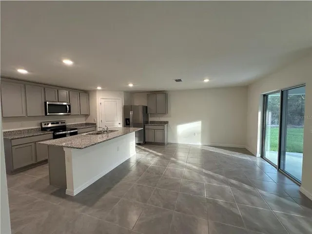 a large kitchen with stainless steel appliances granite countertop a large counter top and a stove top oven