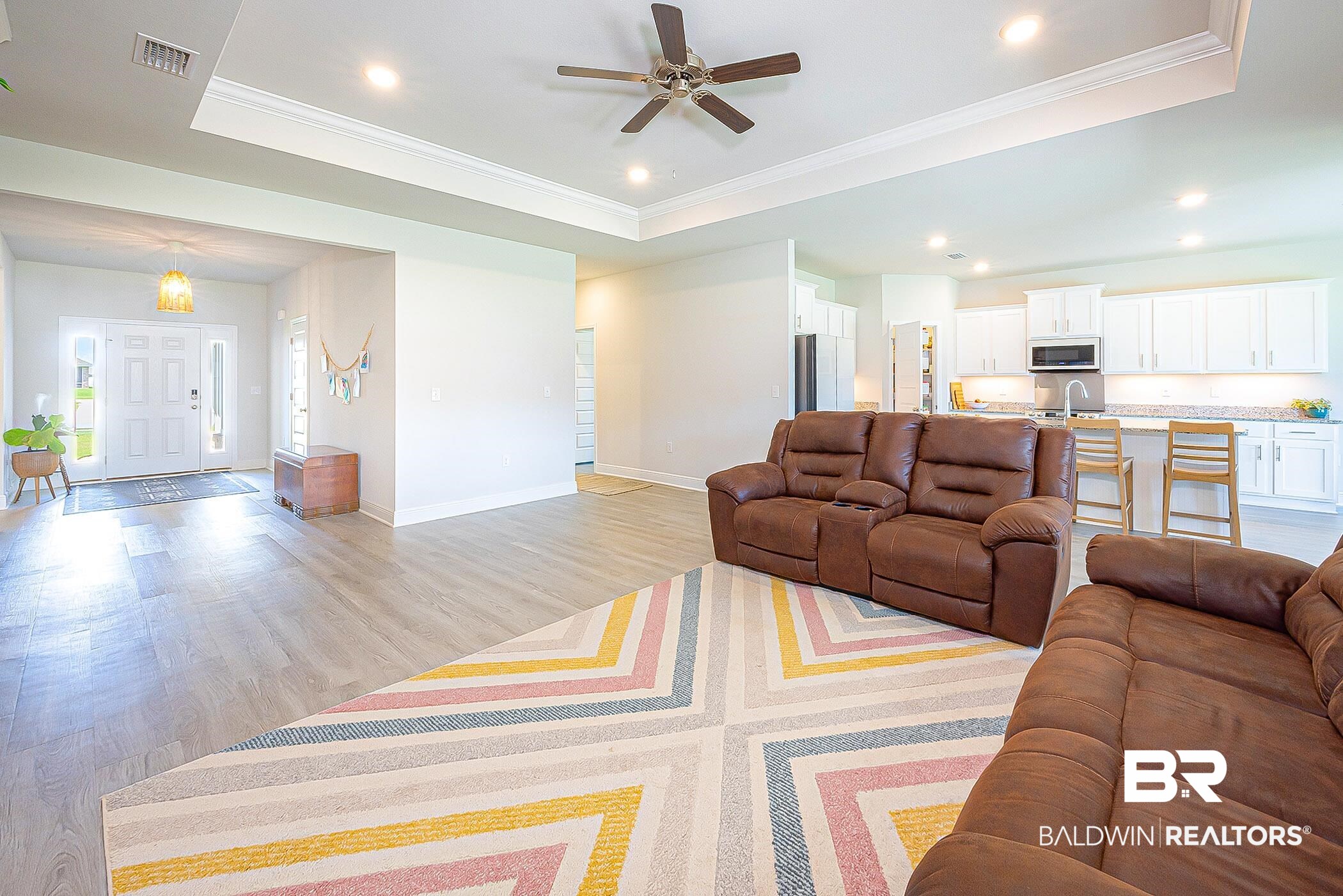 11044 Native Dancer Way Daphne, AL 36526 - Photo 9 of 67 Living room featuring ornamental molding, ceiling fan, light wood-type flooring, and a tray ceiling