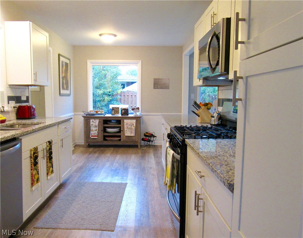 81 Kenridge Road Akron, OH 44333 - Photo 7 of 30 Wide galley kitchen with newer cabinets, granite, backsplash, and stainless steel appliances.