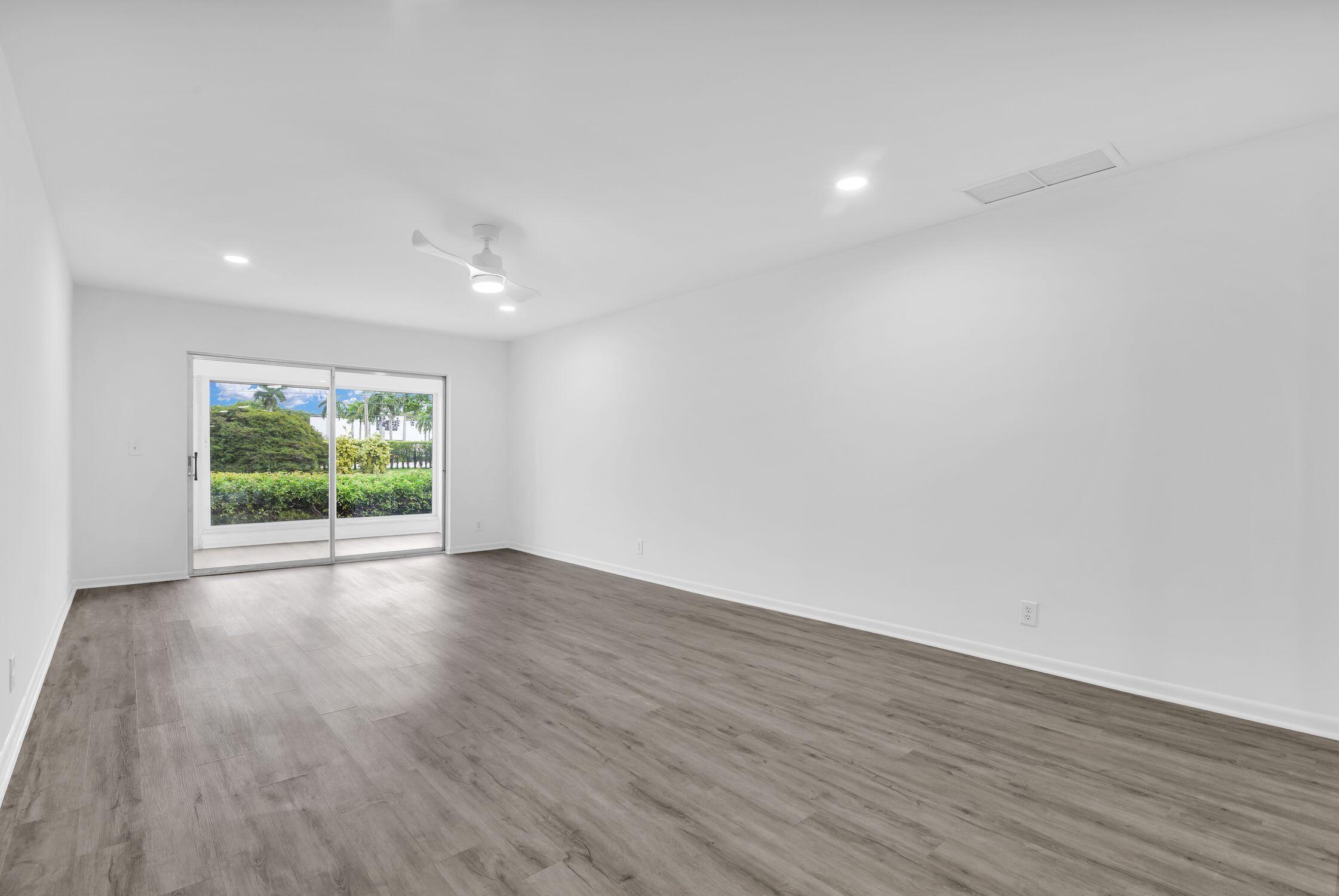 8807 Bella Vista Drive, Unit 280 Boca Raton, FL 33433 - Photo 12 of 44 a view of an empty room with wooden floor and a window