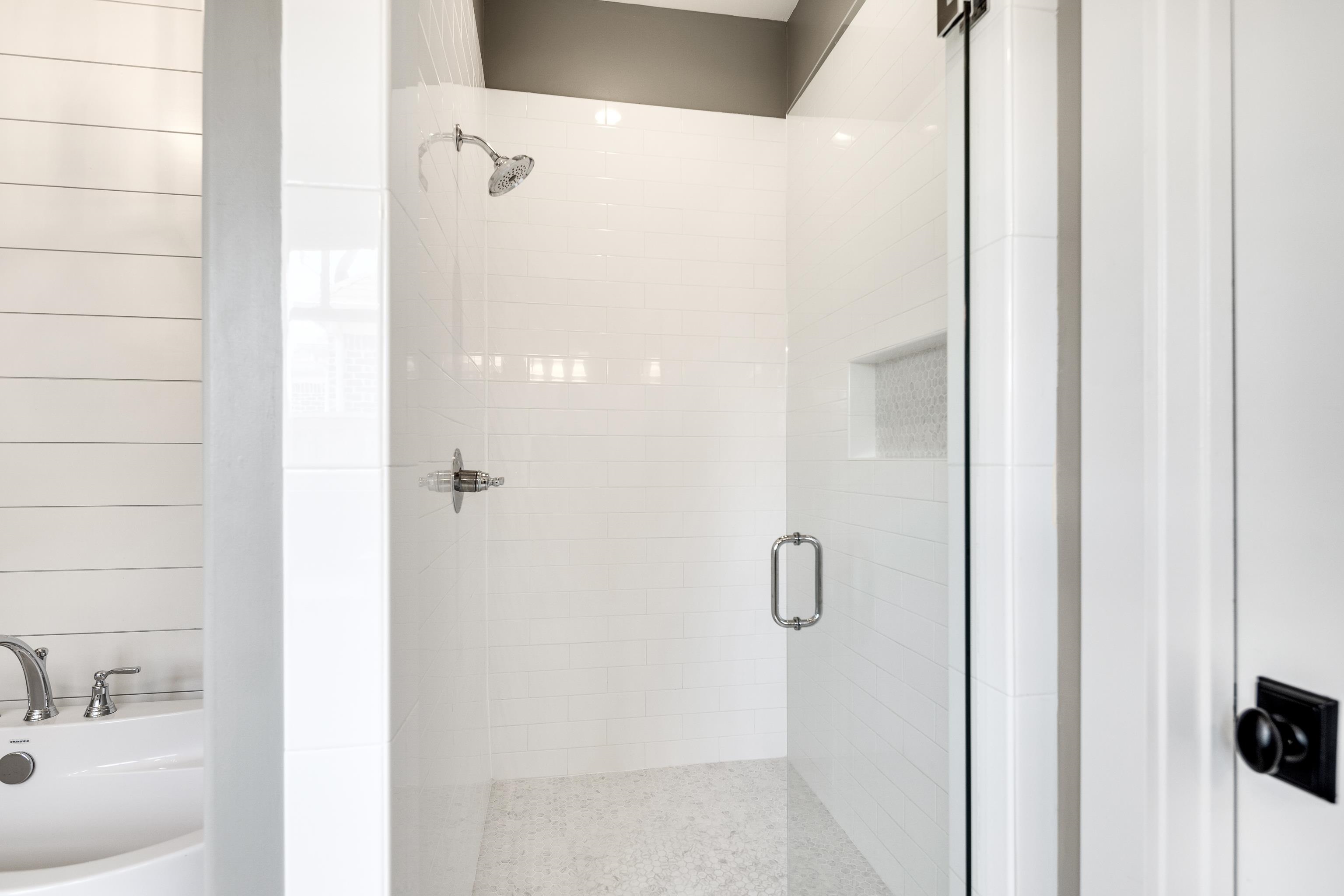 100 Sunflower View Road Piperton, TN 38017 - Photo 21 of 29 Glass-enclosed shower featuring subway tile walls, a built-in niche, and a pebble tile floor