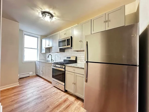 a kitchen with a refrigerator a sink dishwasher a stove and white cabinets with wooden floor
