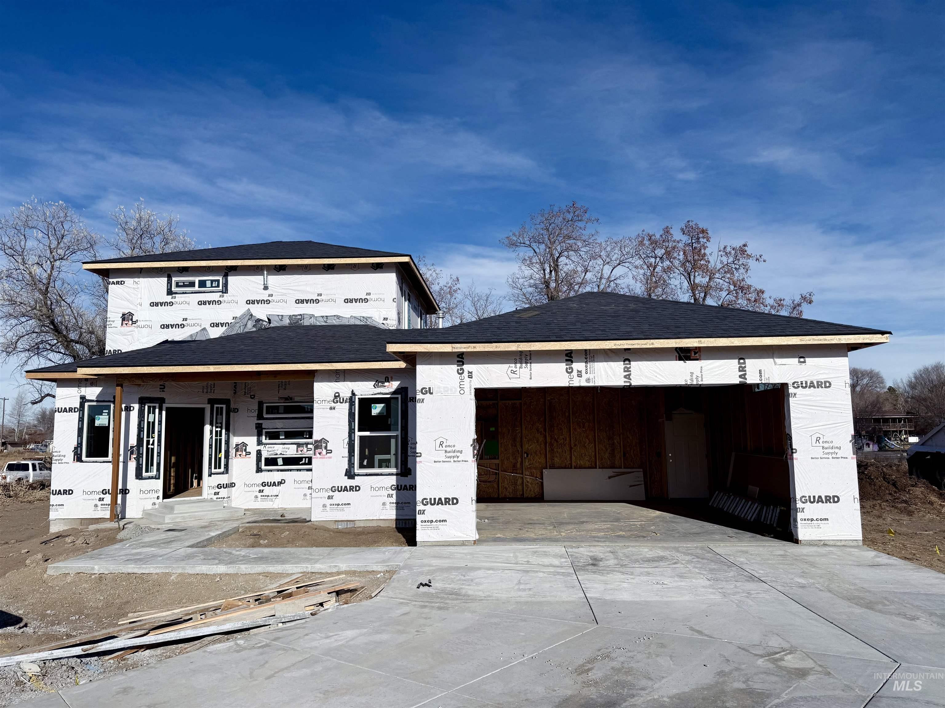 Property in mid-construction featuring a garage, concrete driveway, and roof with shingles