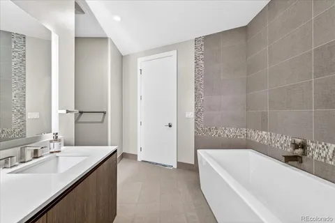 a bathroom with a tub a sink and mirror