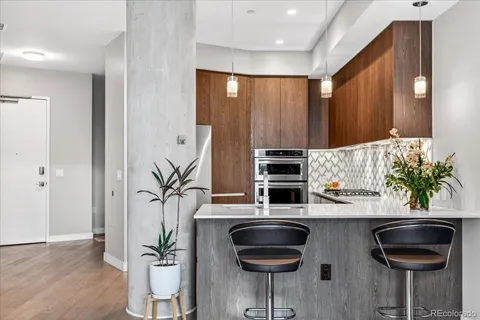 a kitchen with stainless steel appliances a dining table chairs and a refrigerator