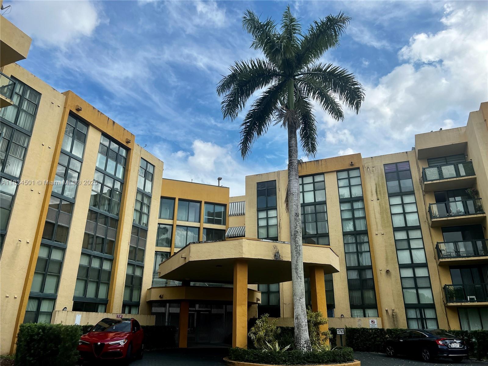 a front view of a building with streets and trees