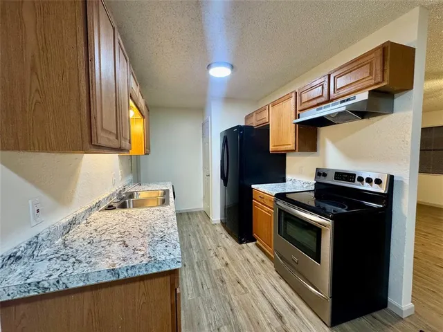 a kitchen with stainless steel appliances granite countertop a stove a sink and a refrigerator