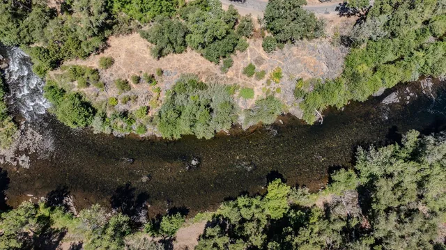 an aerial view of residential house with outdoor space and trees all around