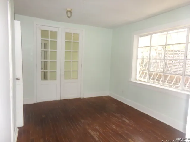 an empty room with wooden floor and windows