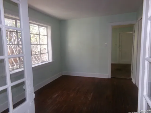 a view of an empty room with wooden floor