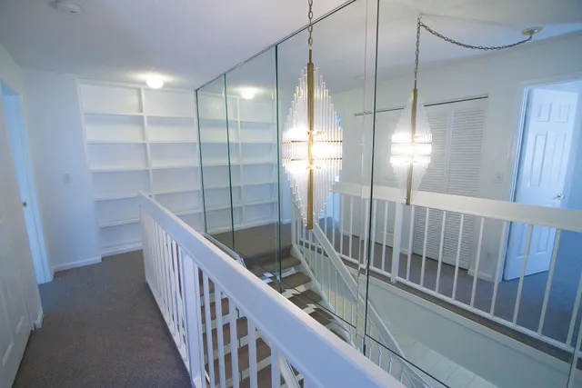 a view of staircase with lots of frames on wall and wooden floor