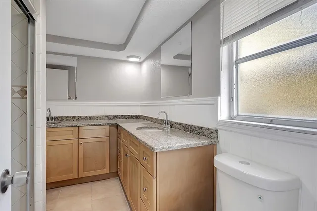 a bathroom with a granite countertop sink a toilet and a mirror