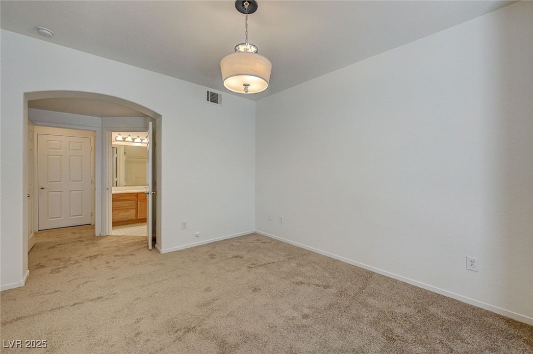6160 Rumrill Street, Unit 232 Las Vegas, NV 89113 - Photo 15 of 26 Empty room with arched walkways and carpet flooring