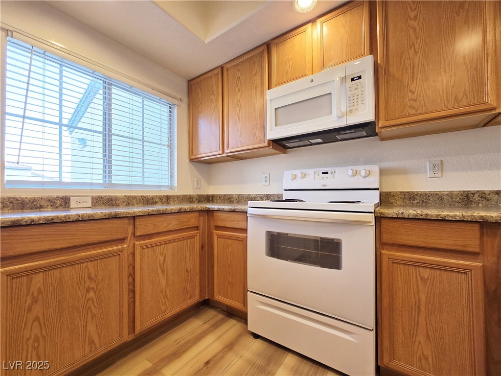 6160 Rumrill Street, Unit 232 Las Vegas, NV 89113 - Photo 3 of 26 Kitchen with white appliances, brown cabinets, and light wood-style floors