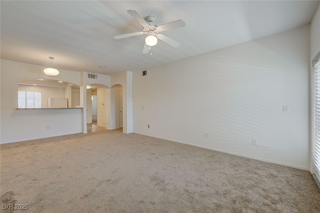 6160 Rumrill Street, Unit 232 Las Vegas, NV 89113 - Photo 8 of 26 Unfurnished living room featuring arched walkways, light colored carpet, and ceiling fan