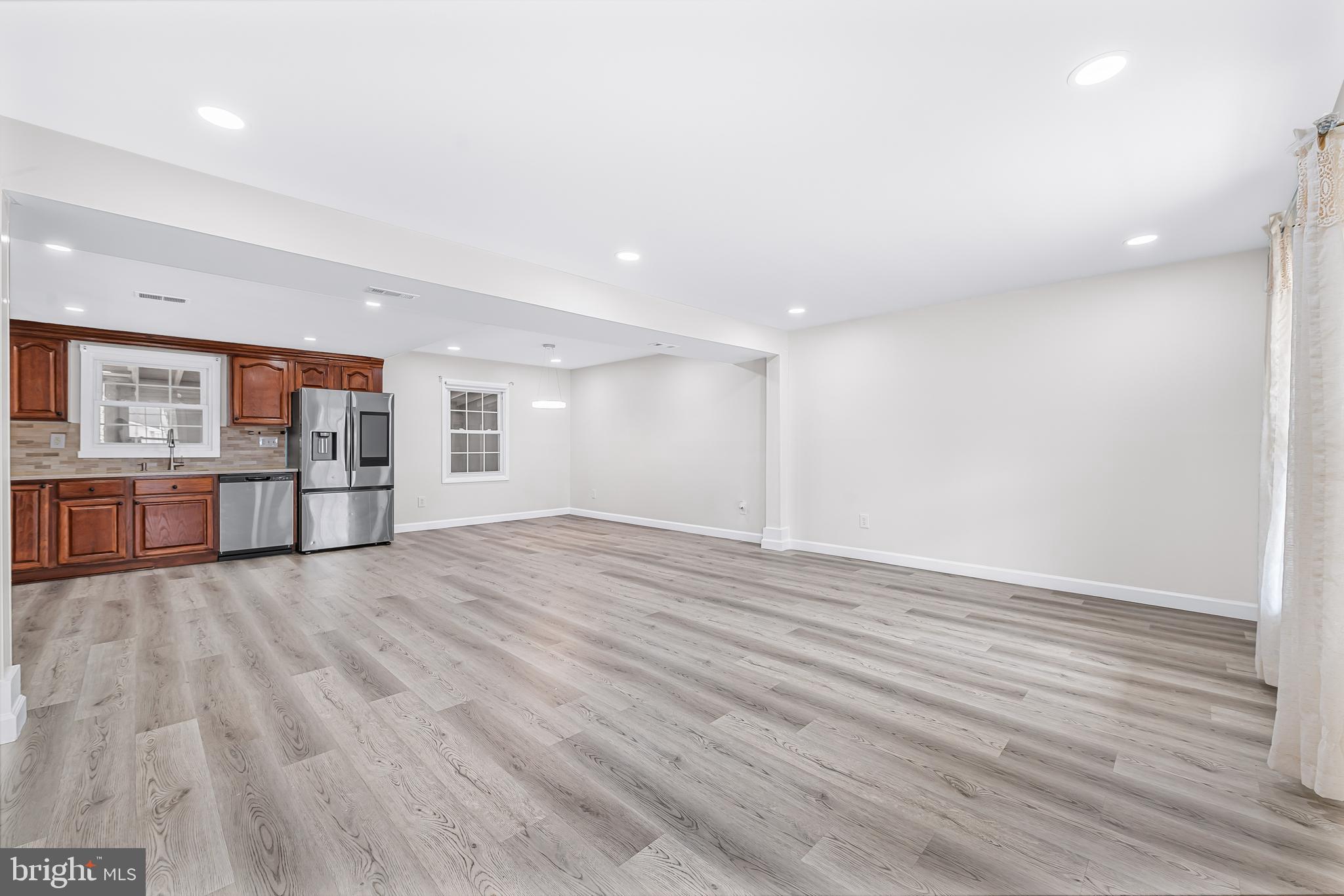 7958 Citadel Drive Severn, MD 21144 - Photo 7 of 32 an empty room with wooden floor and kitchen view